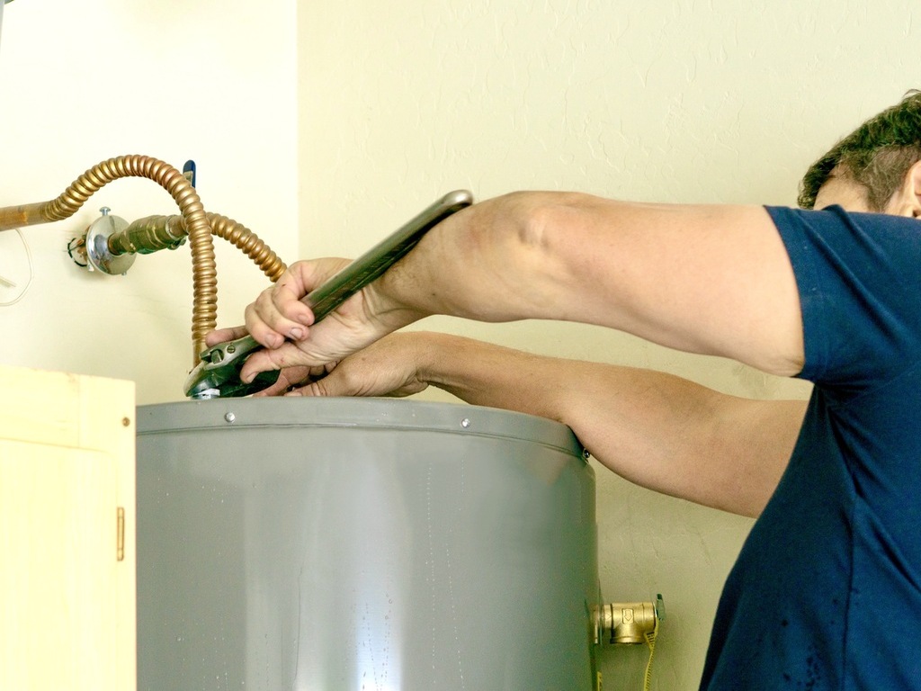 Plumber adjusting a residential water heater during routine maintenance in St. Louis, MO