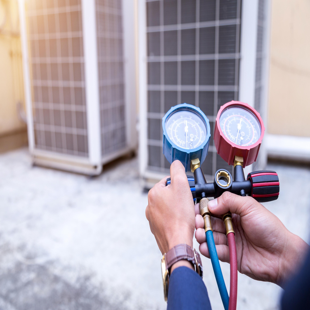 Air conditioning repair technician checking HVAC system pressure during AC service