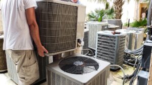 HVAC technicians lifting and installing a residential heating and cooling unit during service visit